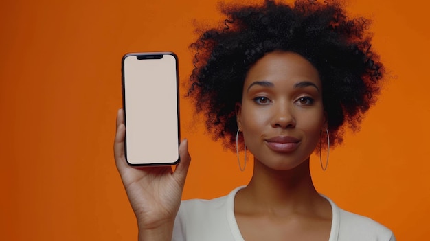 Ad for an app Smiling woman holding white blank smartphone screen close up to the camera orange studio background Gadget with empty space for mockup banner isolated selective focus