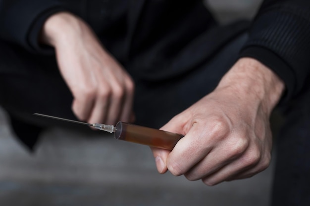 Addict with a syringe in his hands closeup Addiction concept