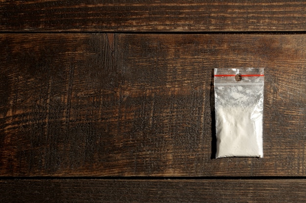 Захватывающие наркотики кокаина в пакете на коричневом деревянном столе. Концепция наркомании