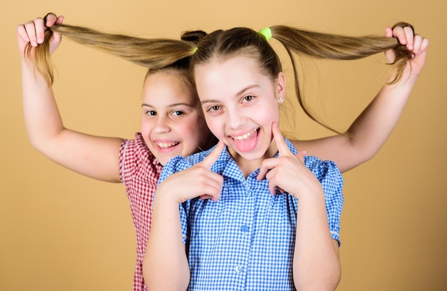 Adding care to her hair Playful little girl keeping long hair of adorable baby Cute happy kid with fashionable hair ponytails Small child smiling with blond hair