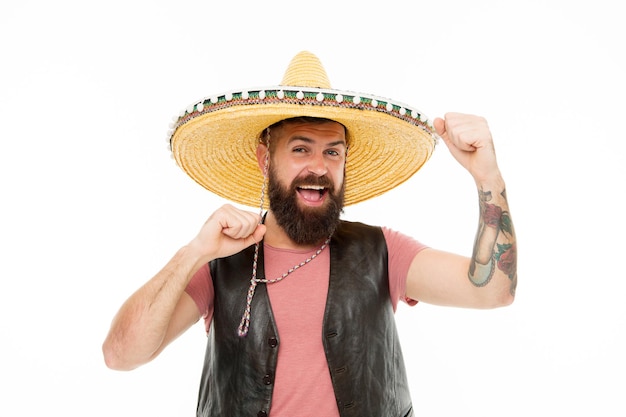 Adding hat to his spanish costume Bearded man smiling in traditional sombrero hat Happy hipster with beard and mustache wearing casual clothes and mexican hat Mexican man in traditional straw hat