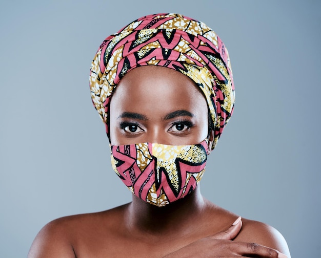 Adding a little beauty to lockdown studio portrait of a beautiful young woman wearing a mask against a grey background