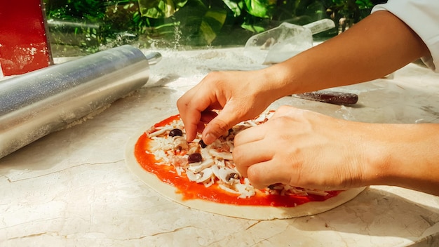 Photo adding olives to unbaked pizza