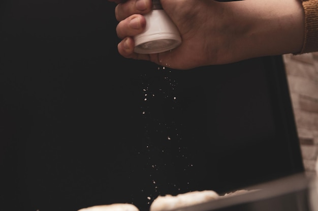 Adding salt. Backlight to salt from salt shaker. Close up