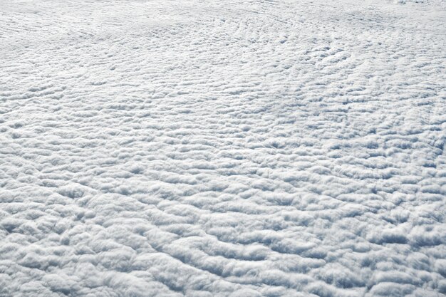 Adembenemend uitzicht over wolken vanuit het vliegtuigraam dikke witte blauwe wolken zien eruit als zacht schuim