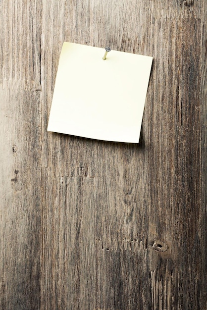 Adhesive note nailed on old wood background