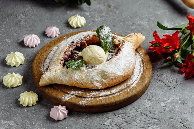 Adjarian zoete khachapuri met ijs, chocolade en pruimen, versierd met munt en koek.