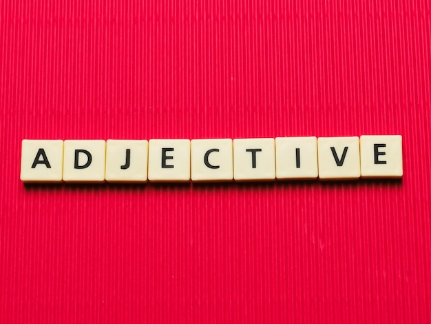 ADJECTIVE word made from square letter tiles on red background.