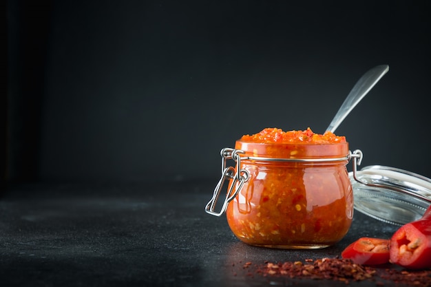 Adjika hot chili peper saus plakken harissa in glazen pot. Tunesië, Georgische en Arabische keuken. Horizontaal.