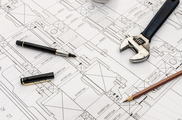 Adjustable key, pen and pencil on blueprint background