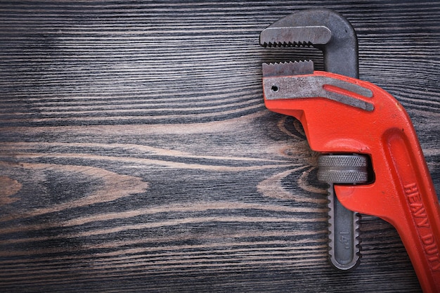 Adjustable pipe wrench on wooden board copy space plumbing concept.