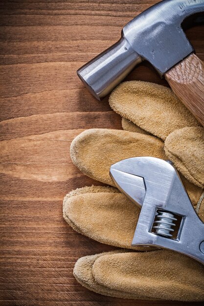 Adjustable spanner claw hammer safety gloves on wooden board