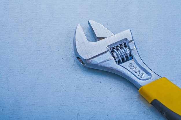 Adjustable spanner on metallic background construction concept