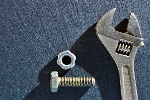 Adjustable spanner and nut on a dark stone background