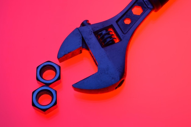 Adjustable wrench and nuts of different sizes on a red backgroundCloseup
