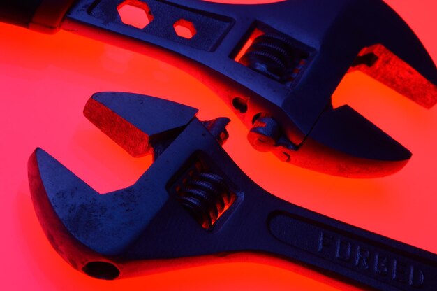 Photo adjustable wrench and nuts of different sizes on a red backgroundcloseup