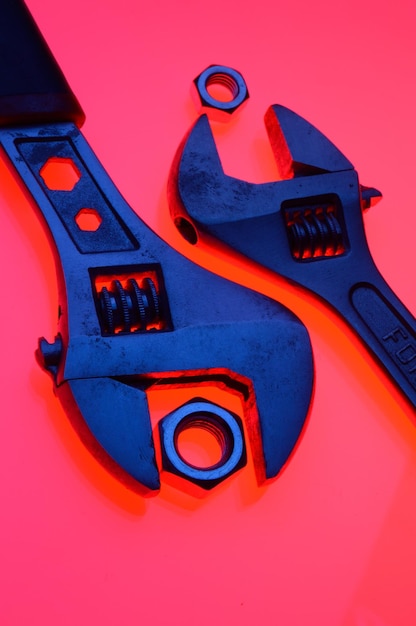 Adjustable wrench and nuts of different sizes on a red backgroundCloseup