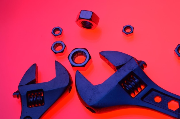 Adjustable wrench and nuts of different sizes on a red backgroundCloseup