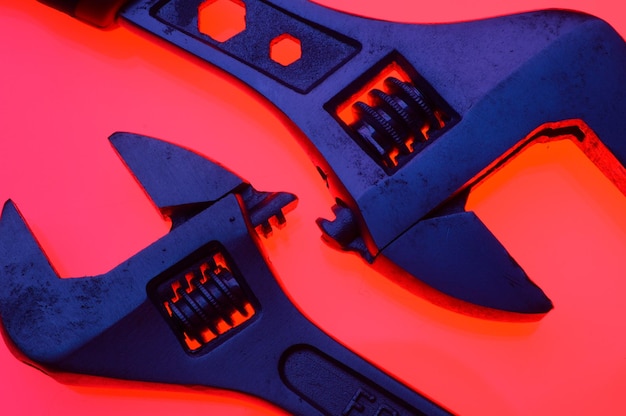 Adjustable wrench and nuts of different sizes on a red backgroundCloseup