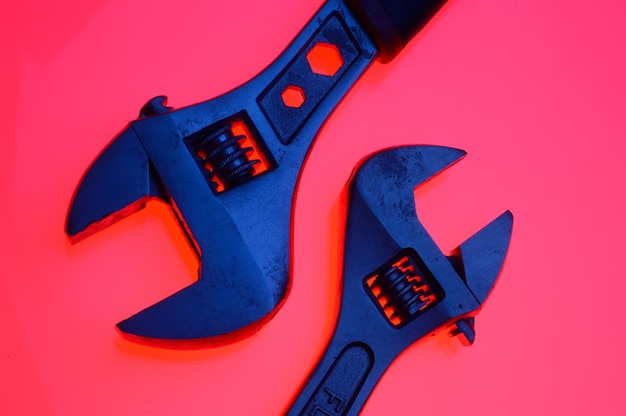 Adjustable wrench and nuts of different sizes on a red backgroundCloseup