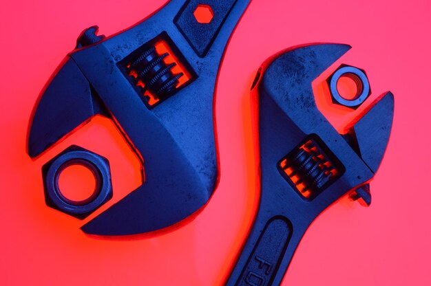 Adjustable wrench and nuts of different sizes on a red backgroundCloseup