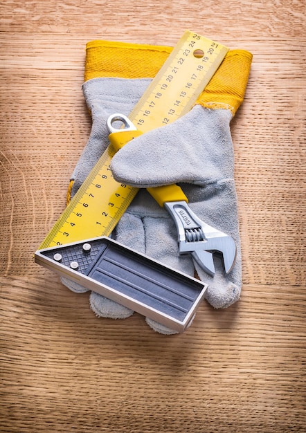 Adjustable wrench square ruller and protective working glove on wooden board construction concept