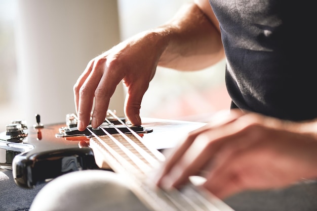 Adjusting guitar closeup of musician hands touching metal strings of guitar gently