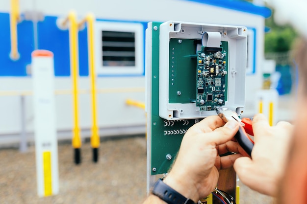 Фото Регулировка контрольно-измерительного оборудования руки электрика или инженера с плоскогубцами за работой крупным планом