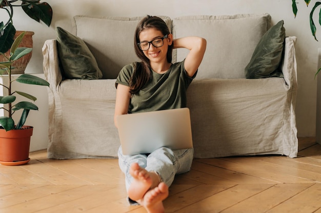 Adolescent female student in eyewear studying online from home using a laptop person