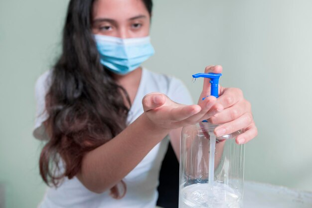 Adolescent Latina woman placing antibacterial gel on her hands as a prevention method