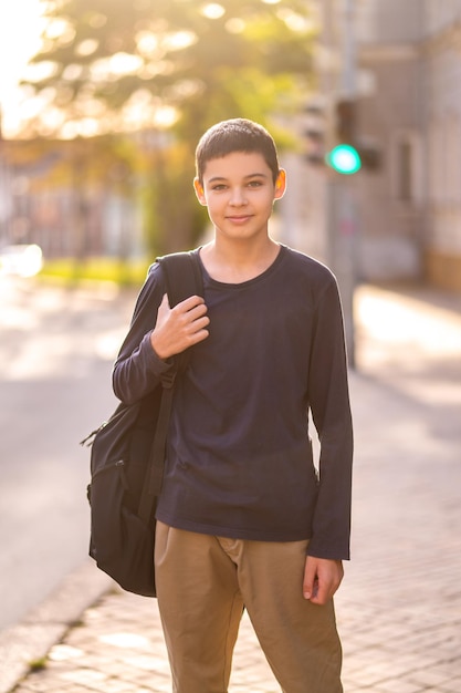 Adolescent with the backpack over the shoulder standing outdoors