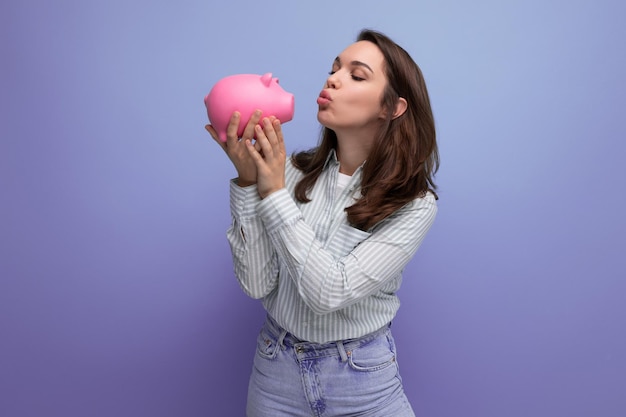 adorable 25 year old brunette woman in a shirt and jeans decides to spend her savings from a piggy bank