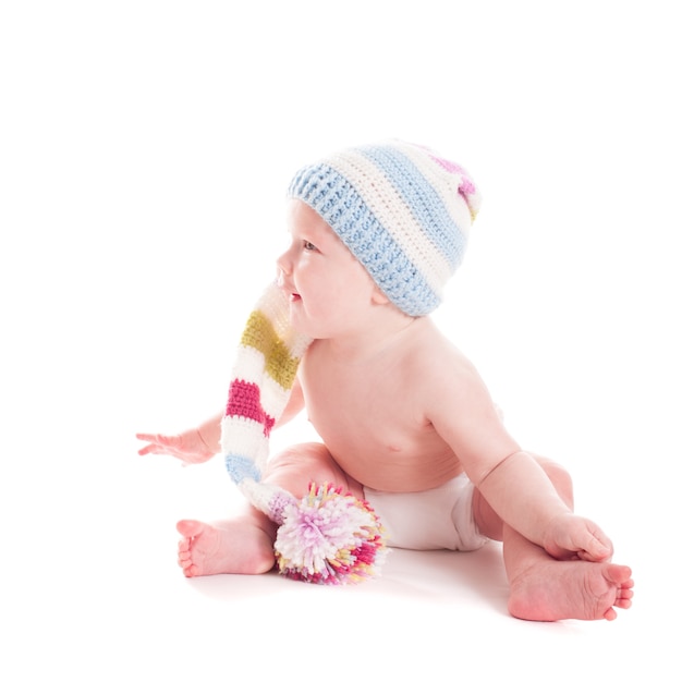 Adorabile bambino di 6 mesi con cappello all'uncinetto distoglie lo sguardo, su bianco