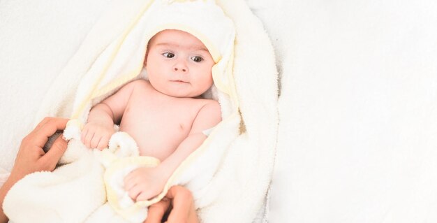 Adorable 6 months old Baby girl infant on a bed on her belly with head up looking into camera with her big eyes Natural light