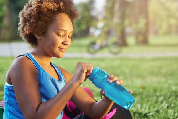 Adorable afro american girl opening bottle of water