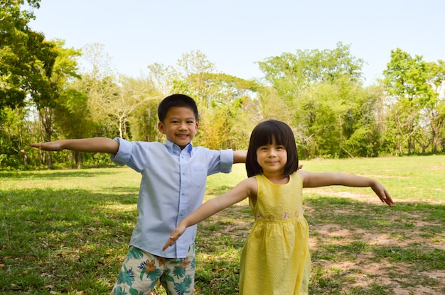 Adorable asian boy and girl standing arms wide open.