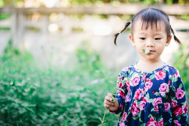 사랑스러운 아시아 여자는 정원 야외에서 잔디와 꽃과 함께 즐길 수