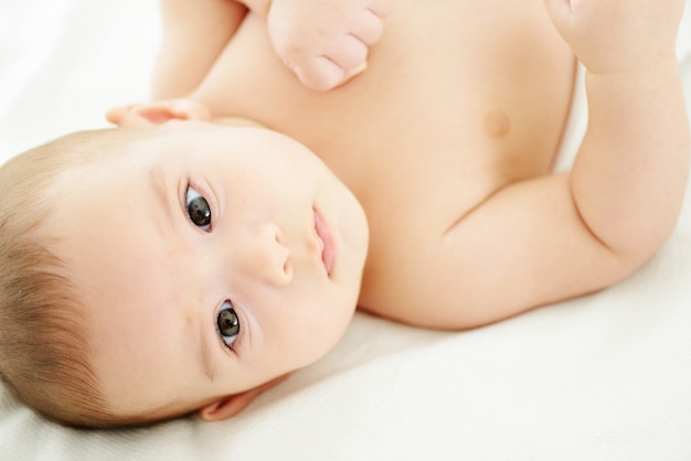 Adorable baby boy closeup portrait on white sheet