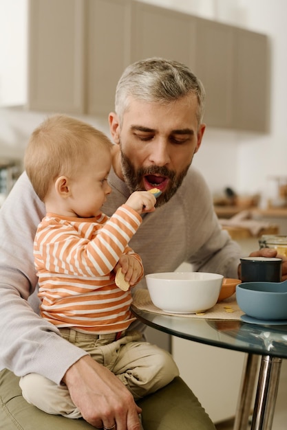 Adorable baby boy feeding his father