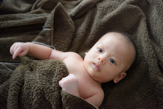 Adorable baby boy under a hooded towel after bath