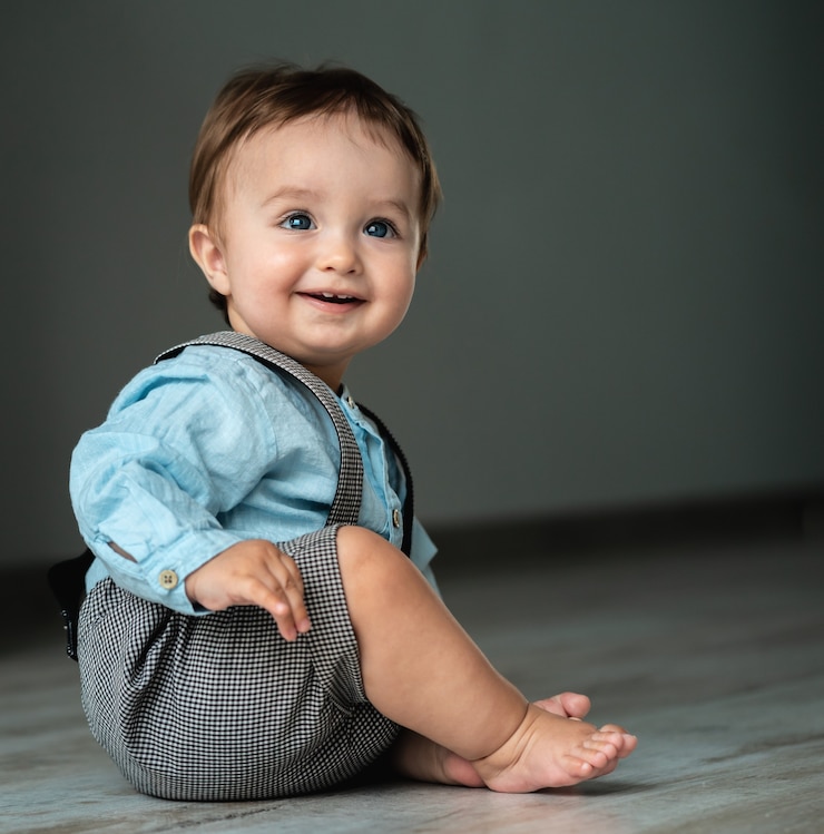 愛らしい男の子が床に座っています