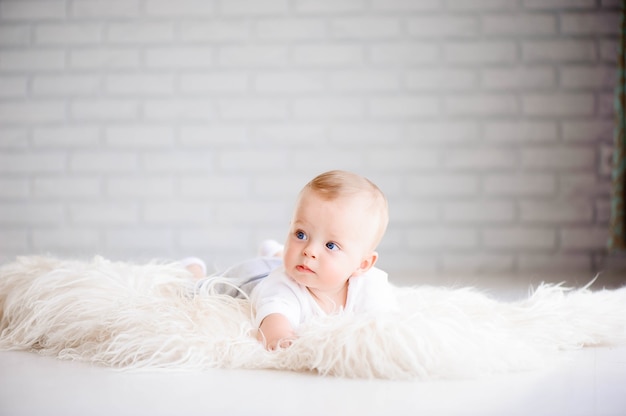 Adorable baby boy learning to crawl and playing in white sunny bedroom