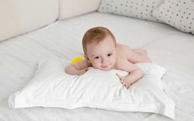 Adorable baby boy relaxing on big pillow after bathing