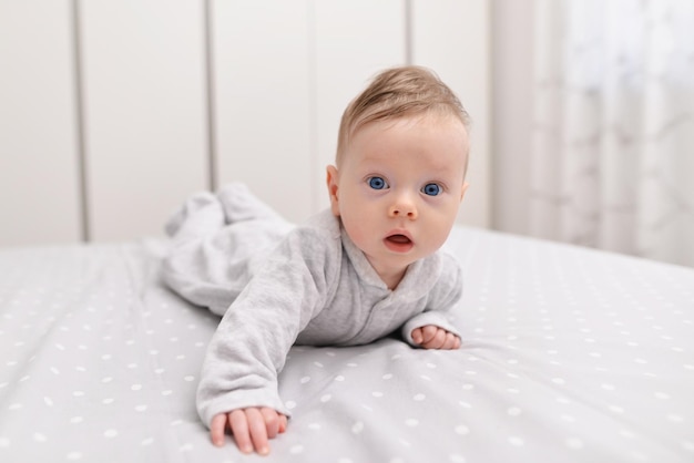 Adorabile bambino in camera da letto bianca e soleggiata neonato rilassante a letto mattina in famiglia a casa