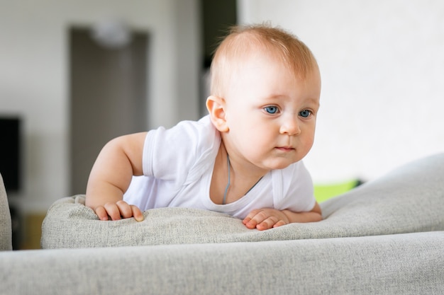 Adorable baby boy in white sunny bedroom. Newborn child relaxing on a blue bed. Nursery for young children.