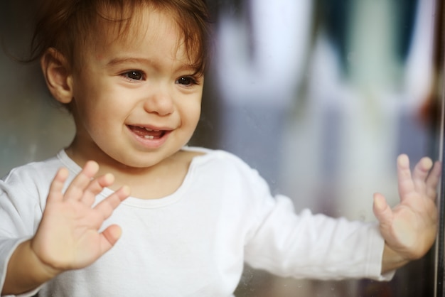 Adorable baby boy on window glass