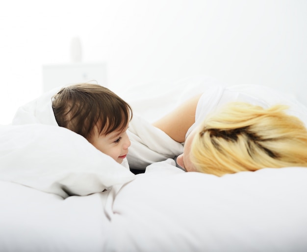 Adorable baby boy with mom on bed