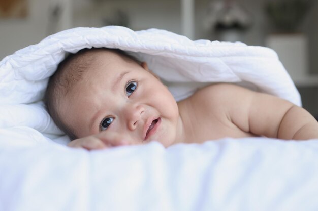 Adorable baby crawling on the bed body covered by the blanket Happy moments