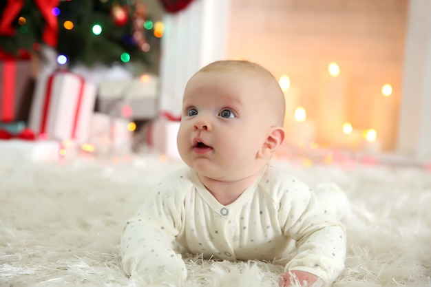장식된 크리스마스 방 바닥에 있는 사랑스러운 아기