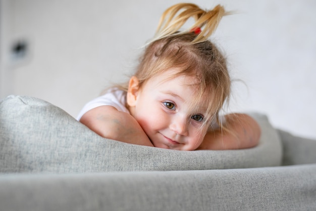 白い日当たりの良い寝室で愛らしい女の赤ちゃん。生まれたばかりの子供が青いベッドでリラックス。幼い子供のための保育園。